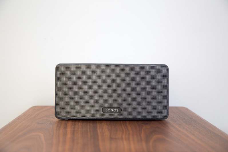 Diverse team testing smart speakers in a modern home office environment with notebooks and audio equipment